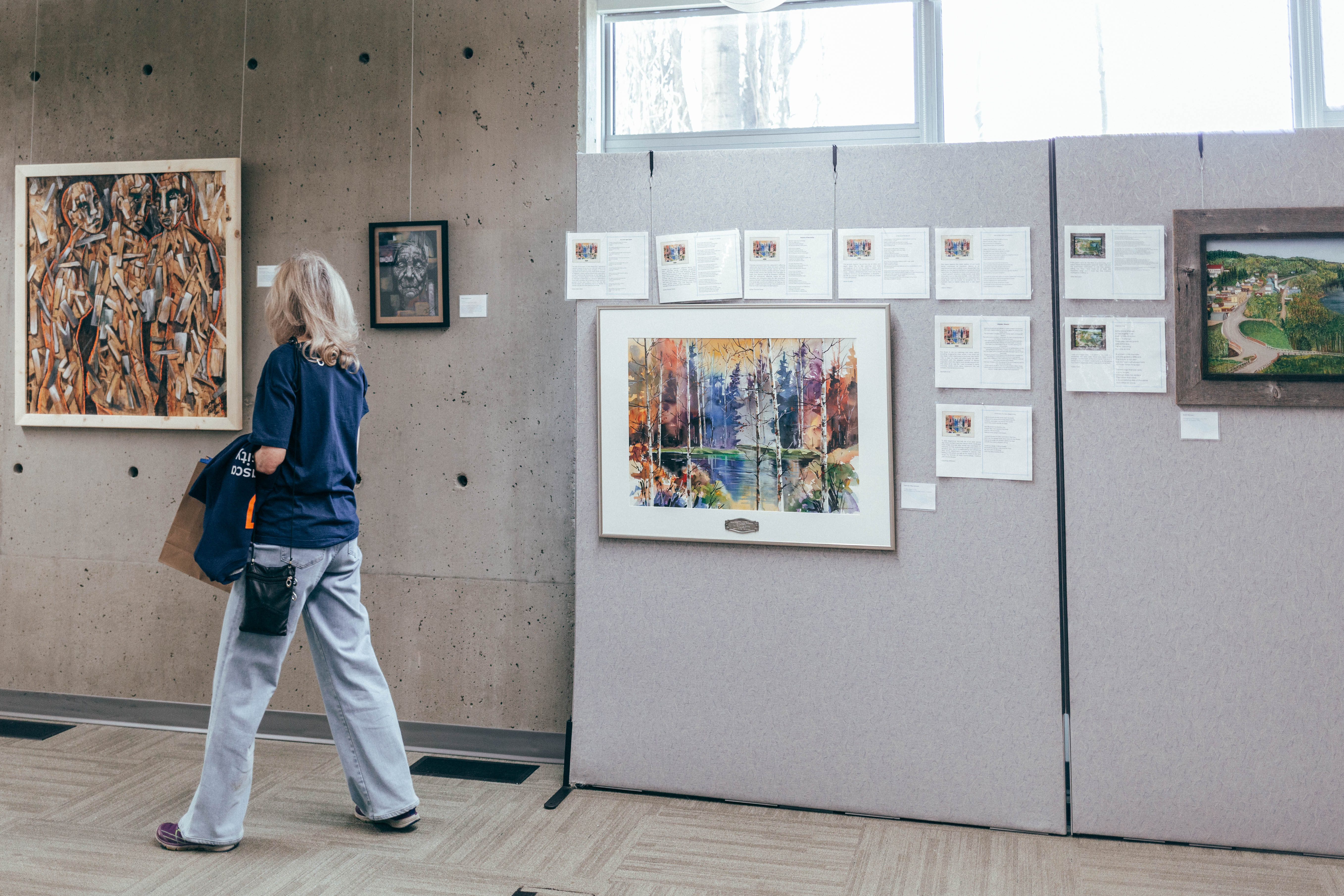 An attendee holding an AU sweater and looking at art in ARC
