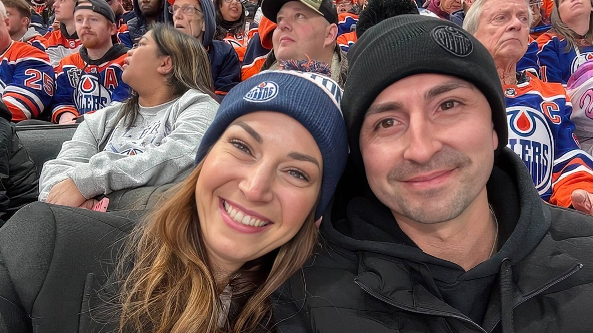 Brittany and her husband Alexander sitting together in the stands at an Edmonton Oilers hockey game