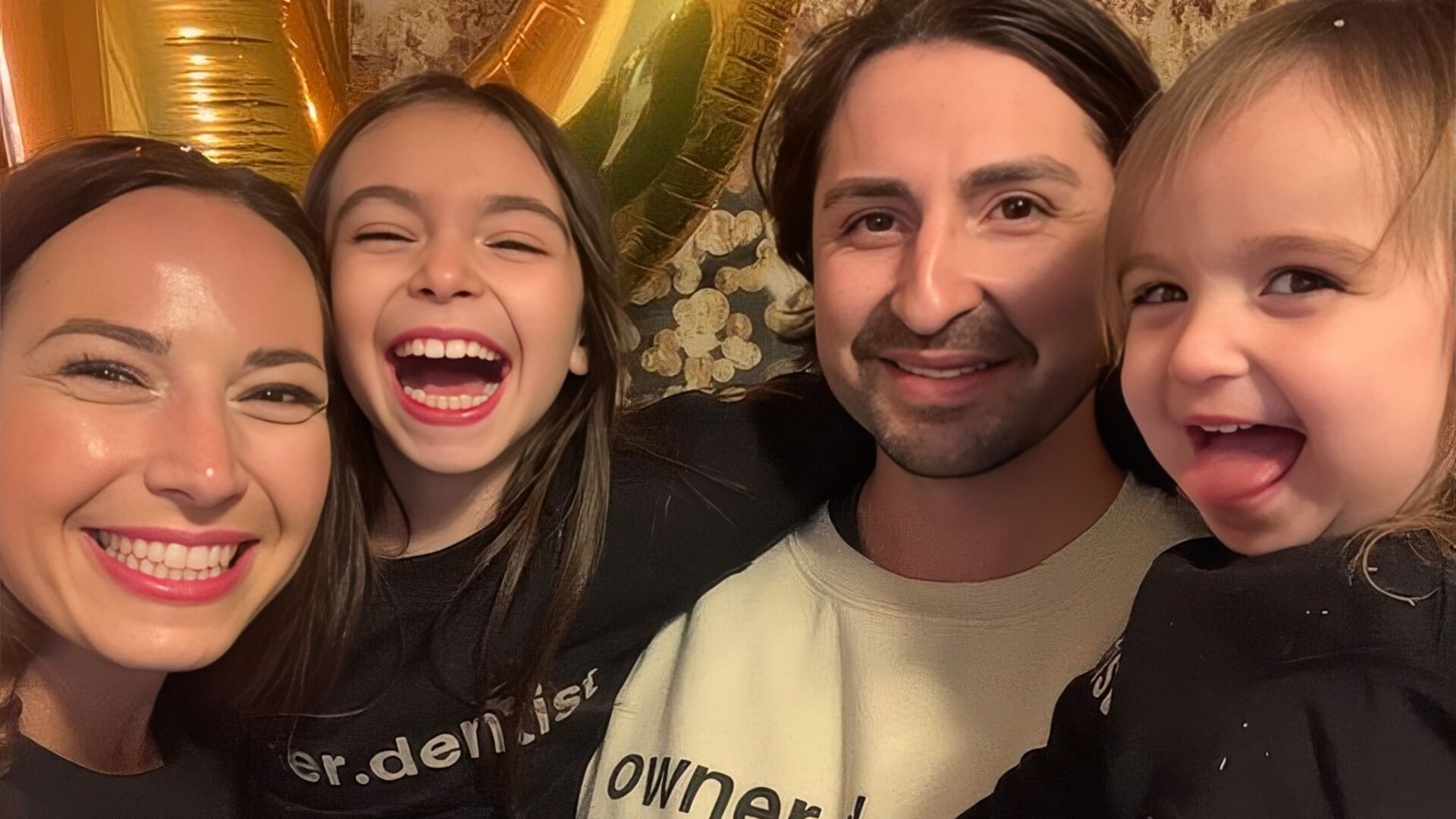 Brittany with her two daughters and husband all wearing owner dentist branded sweatshirts