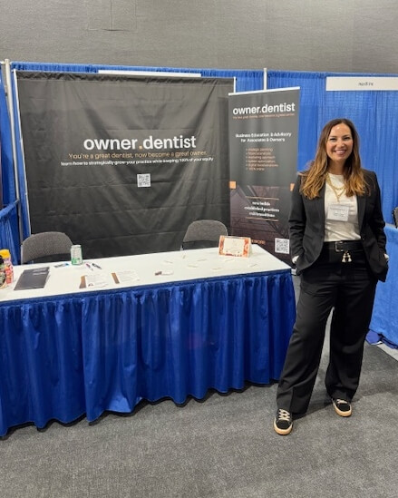 Brittany Encina at a tradeshow standing in front of her Owner Dentist booth