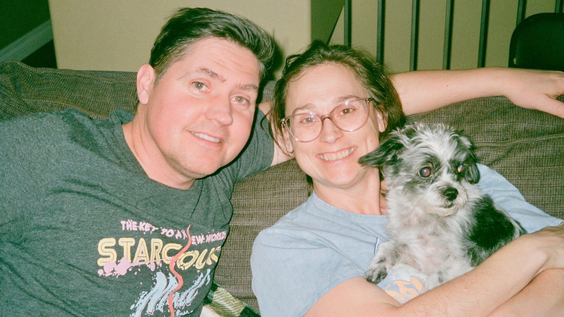 Carrie Bueckert with her husband and dog sitting on a couch