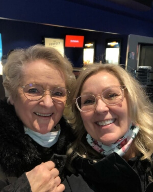 A close-up photo of Cori Francis (right) with her mother (left), both smiling, in movie theatre lobby