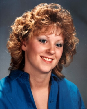 Cori Francis with medium-length blond hair wearing a blue v-neck shirt and 