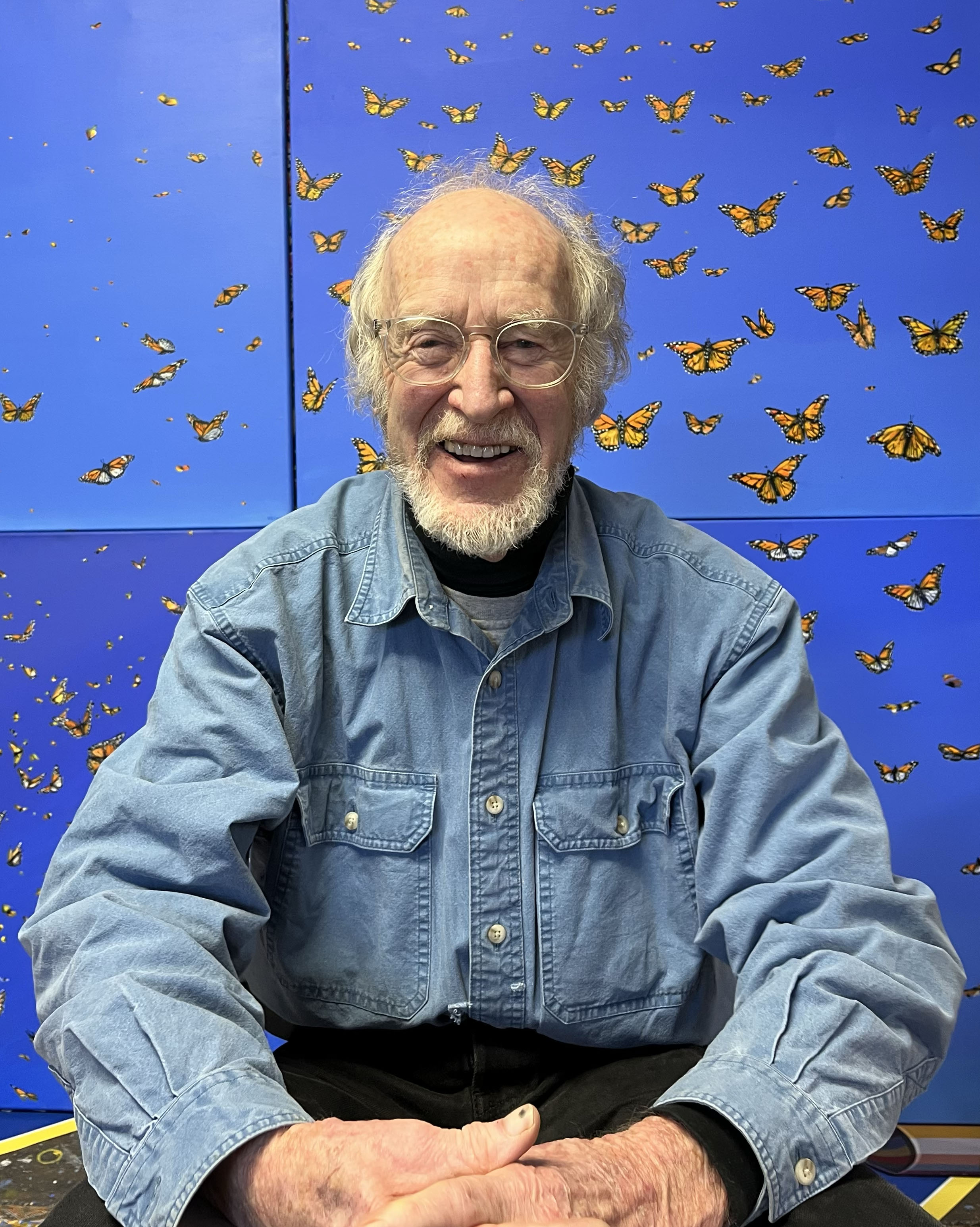 Sylvain Voyer sitting in front of his art