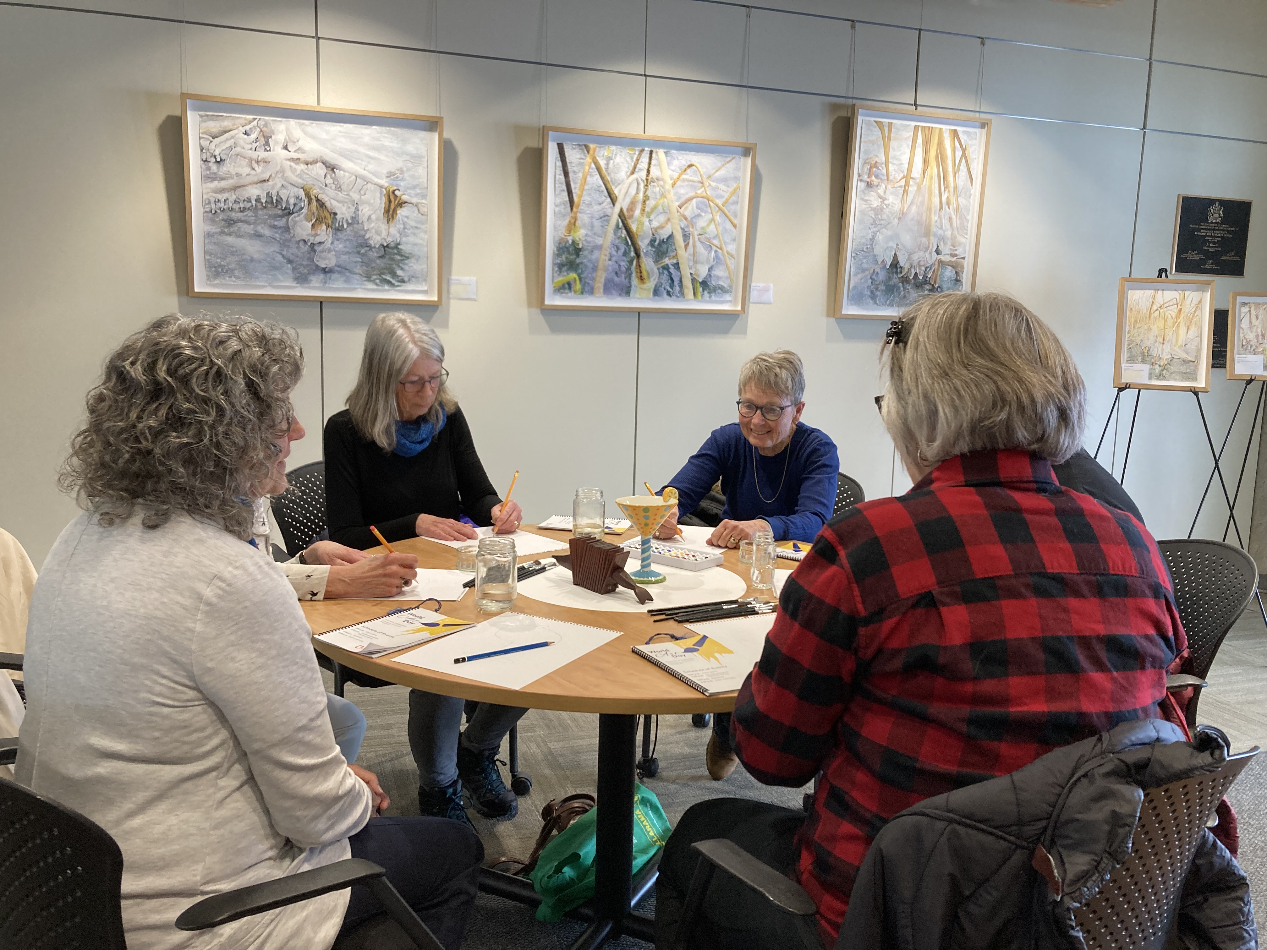 A group sitting at a table and working on Harvey's art demonstration