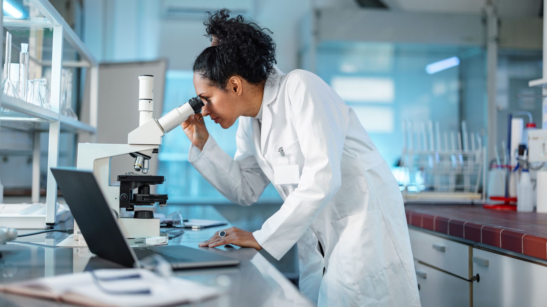 A woman looking into a microscope in a science lab