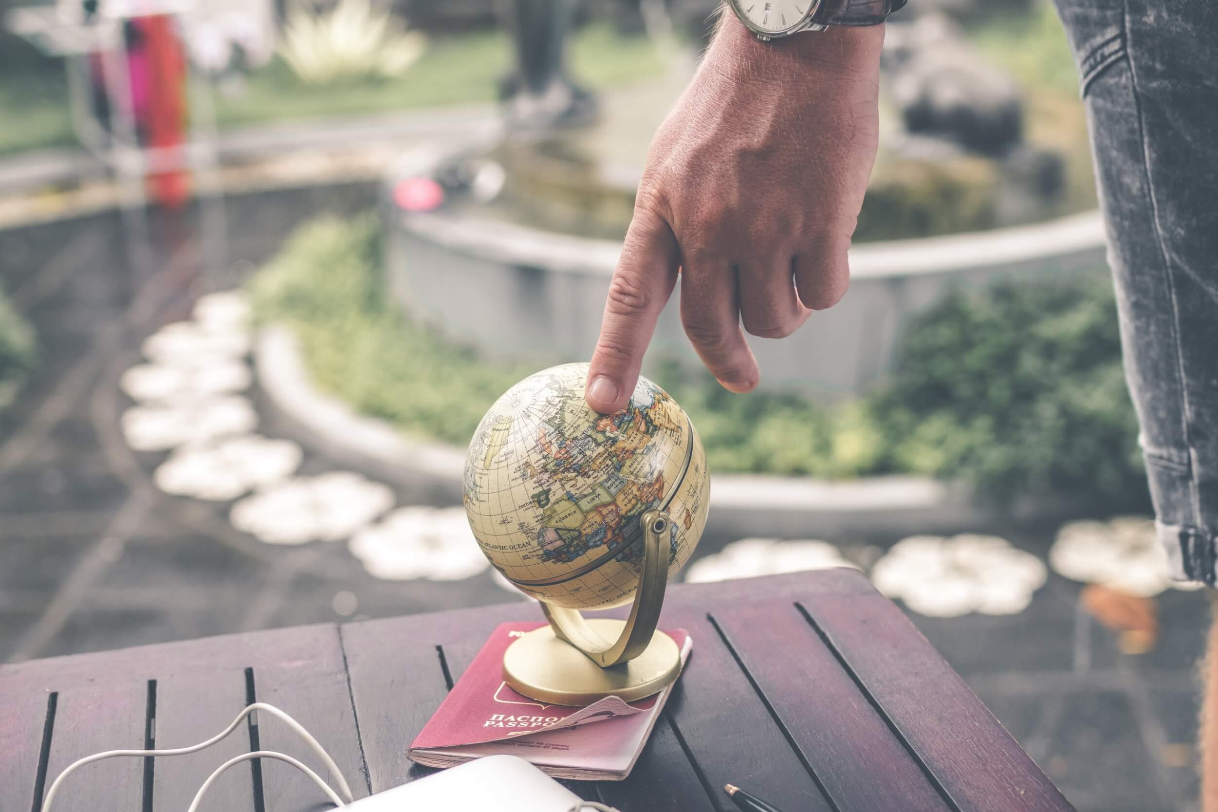 Person with their finger on a small globe