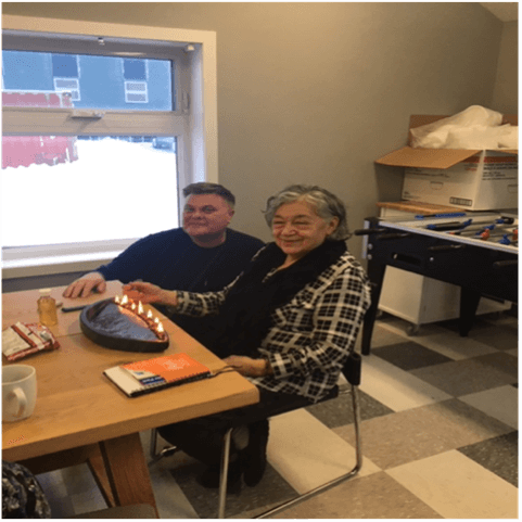 Wayne Clark with Elder Nevinia Brown sitting at a table next to a window.