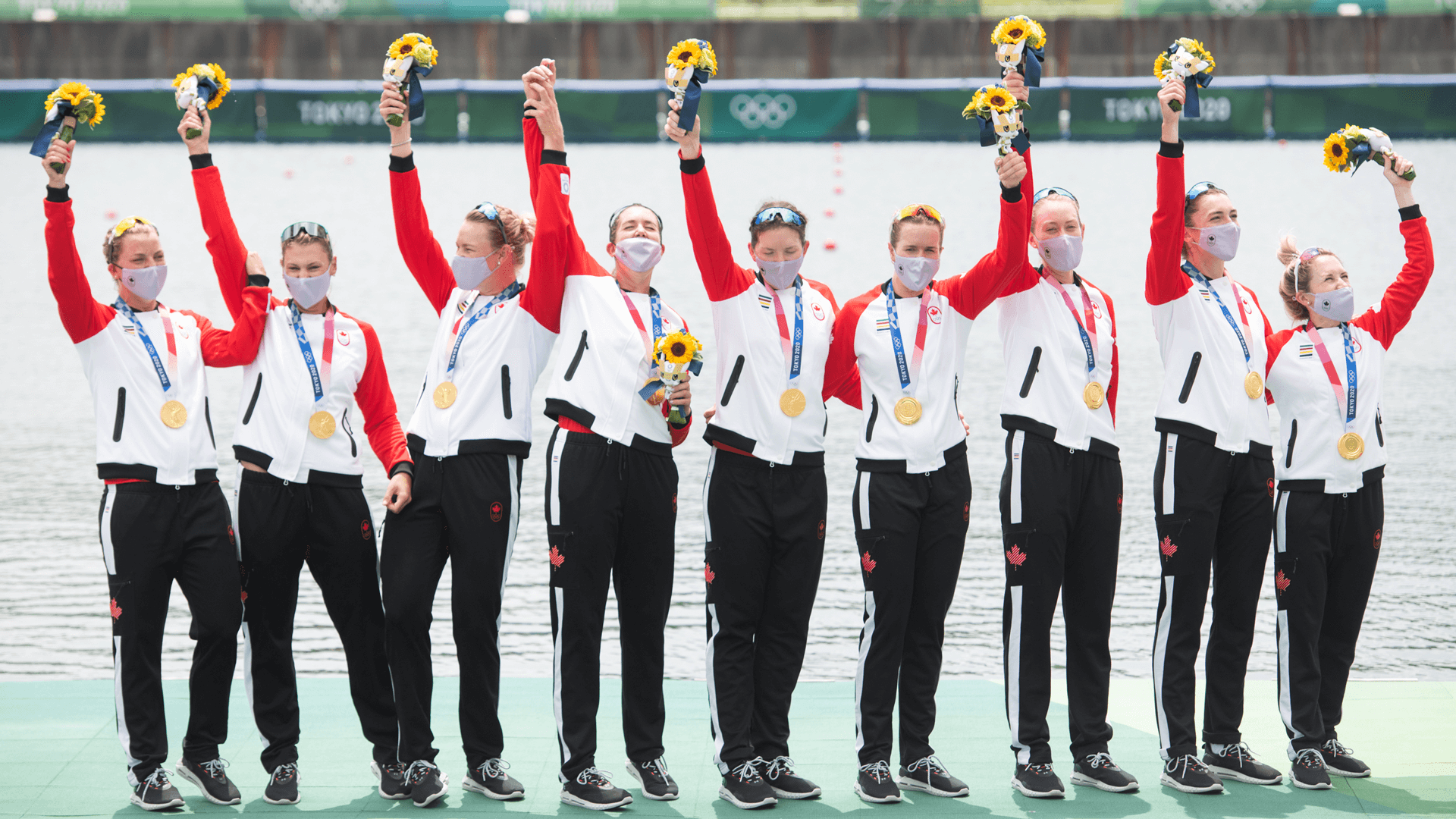 Canadian women's eight rowing team with their gold medals and holding flowers