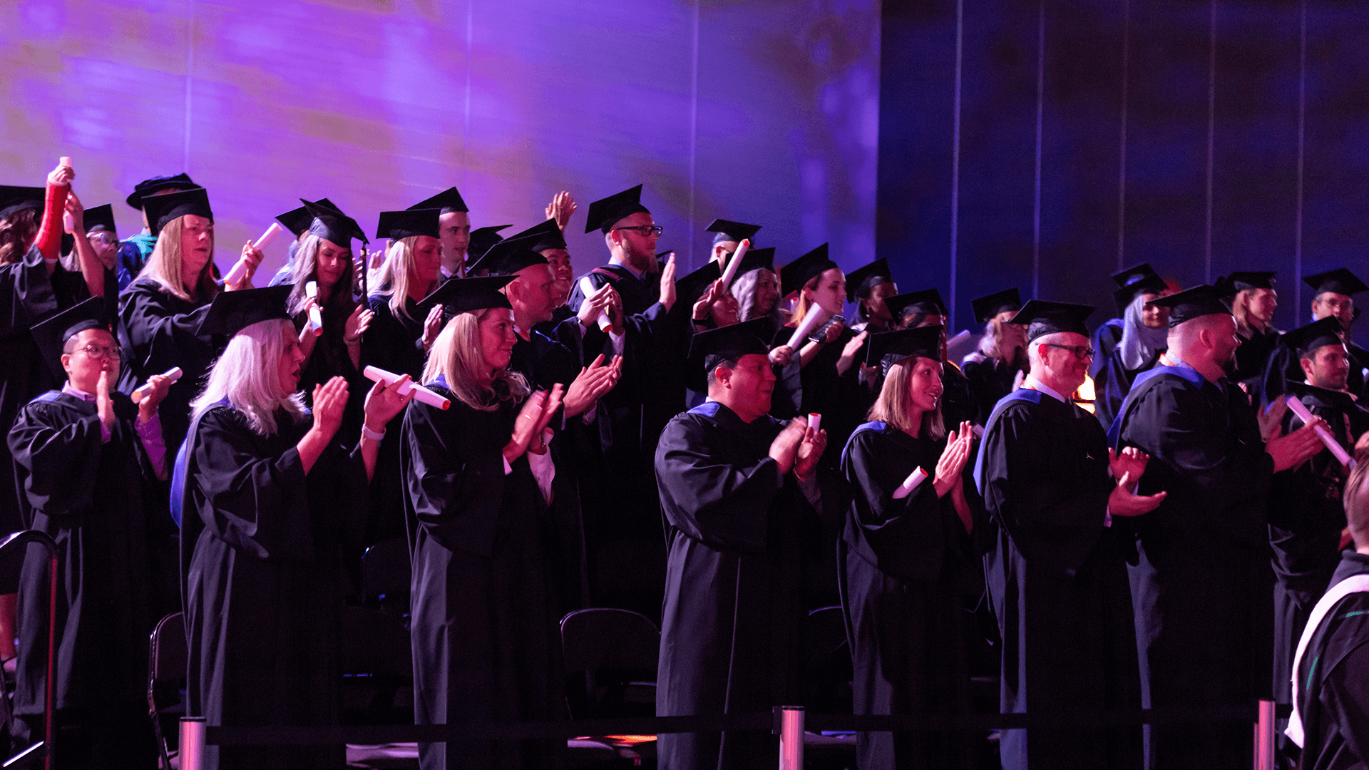 group shot of graduates standing and clapping