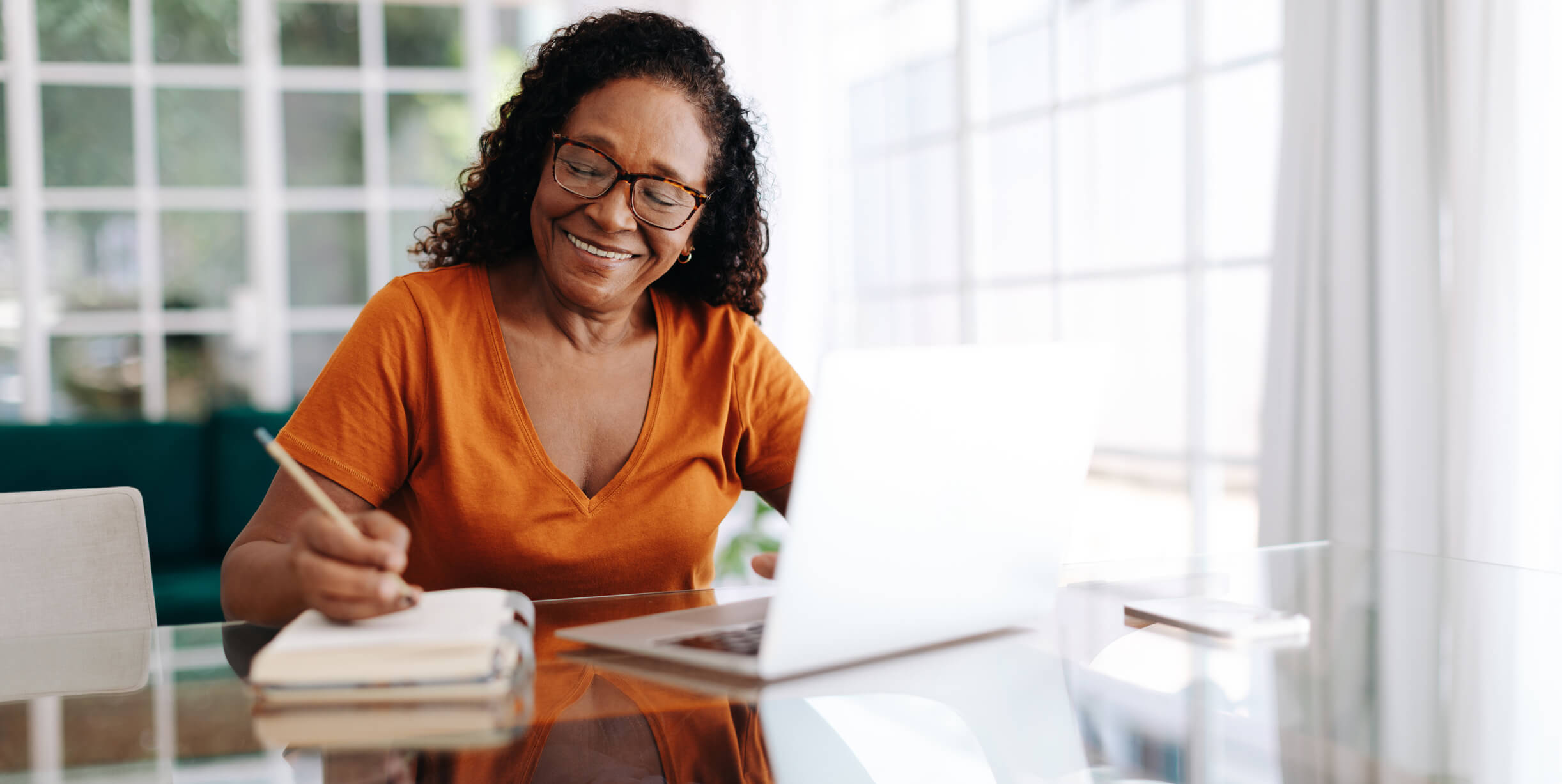 Happy senior woman sitting at a table in her home office, drafting