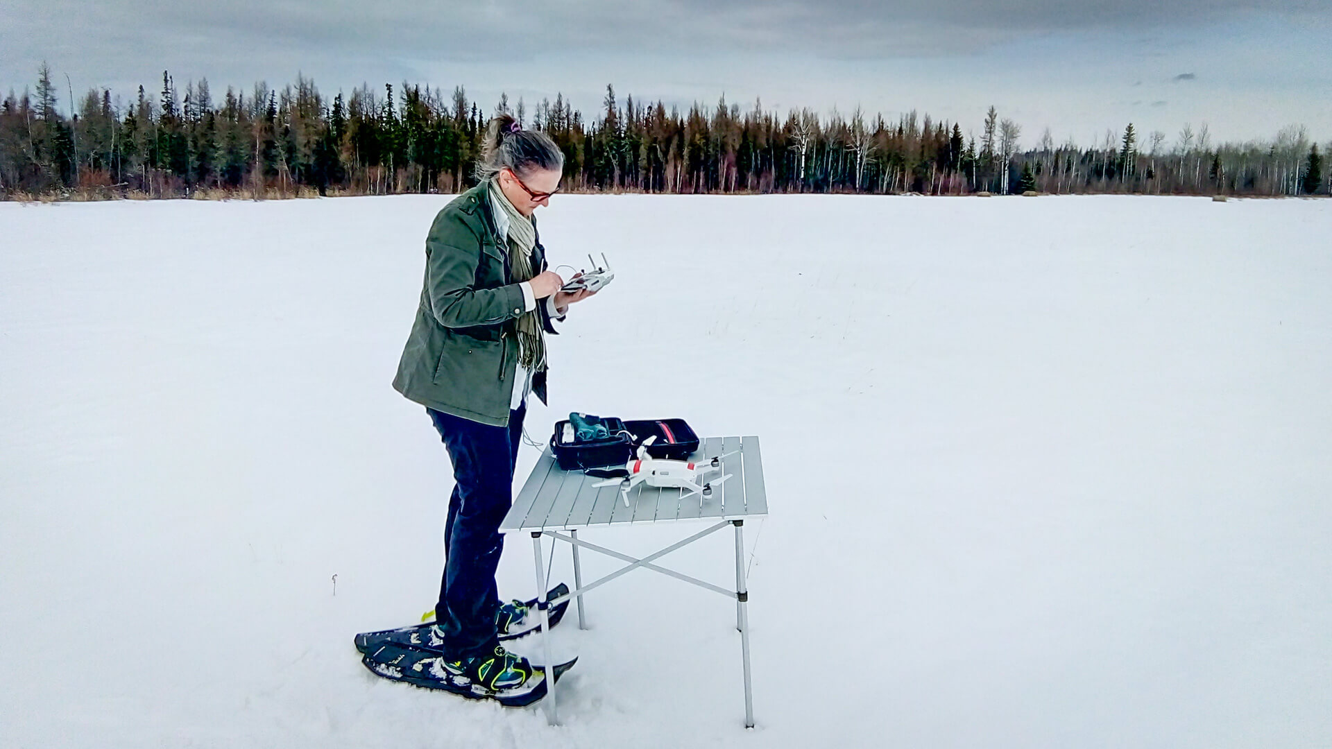 Dr. Frédérique Pivot holding a drone in front of a table in the middle of a snowy field in winter