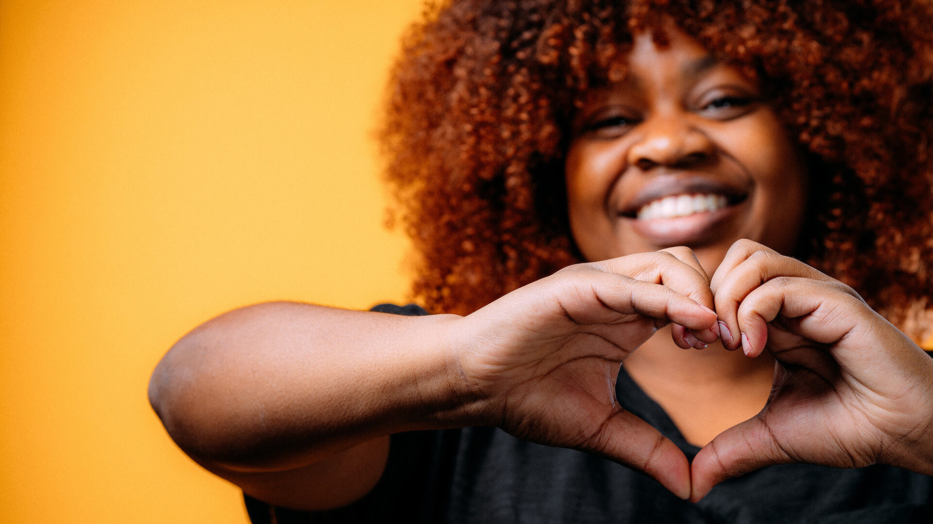 Black woman making a heart shape with her hands