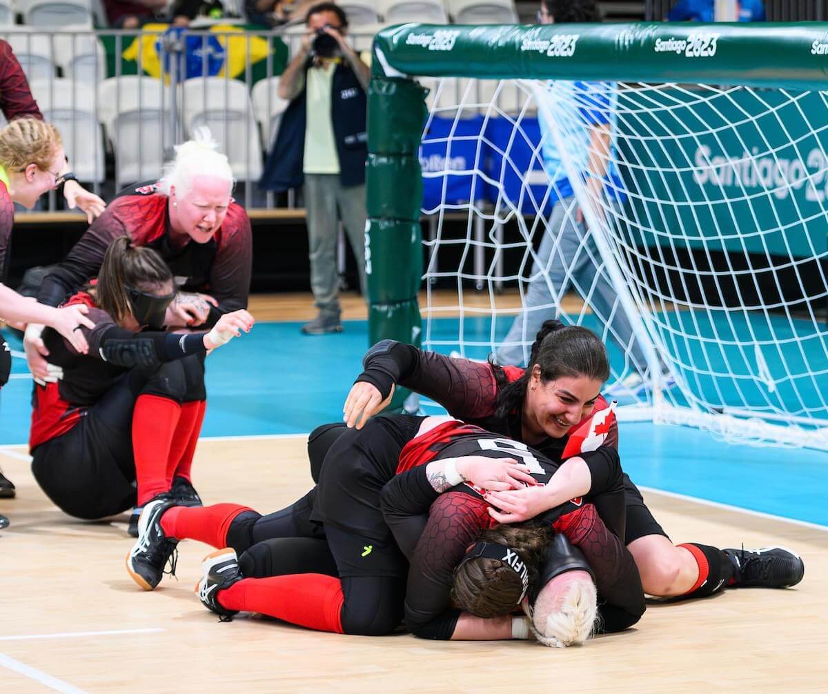Team Canada in Goalball celebrating on the ground in a team pile