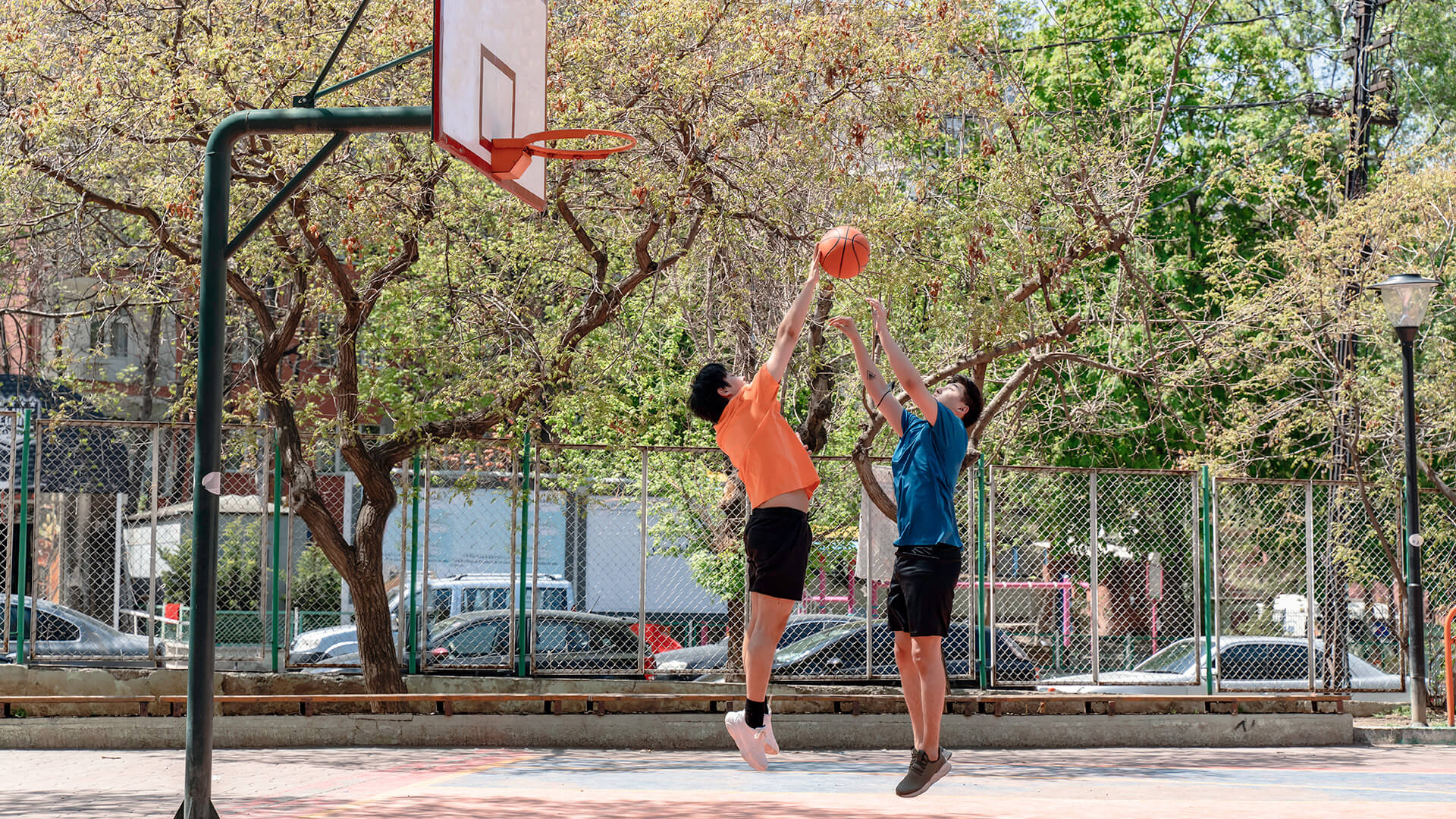 Young male adults playing basketball outdoors