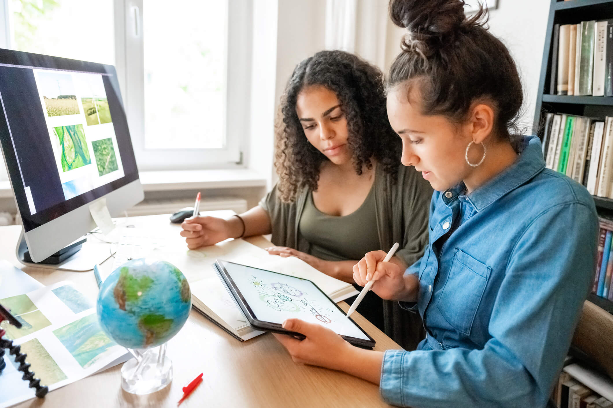 two young woman working together on concepts for climate protection two young woman preparing together concepts for climate protection on desk indoors