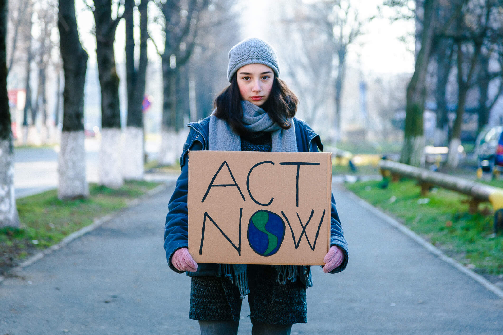 Young activist holding sign protesting against climate change Portrait of a young teenage girl activist holding a sign saying