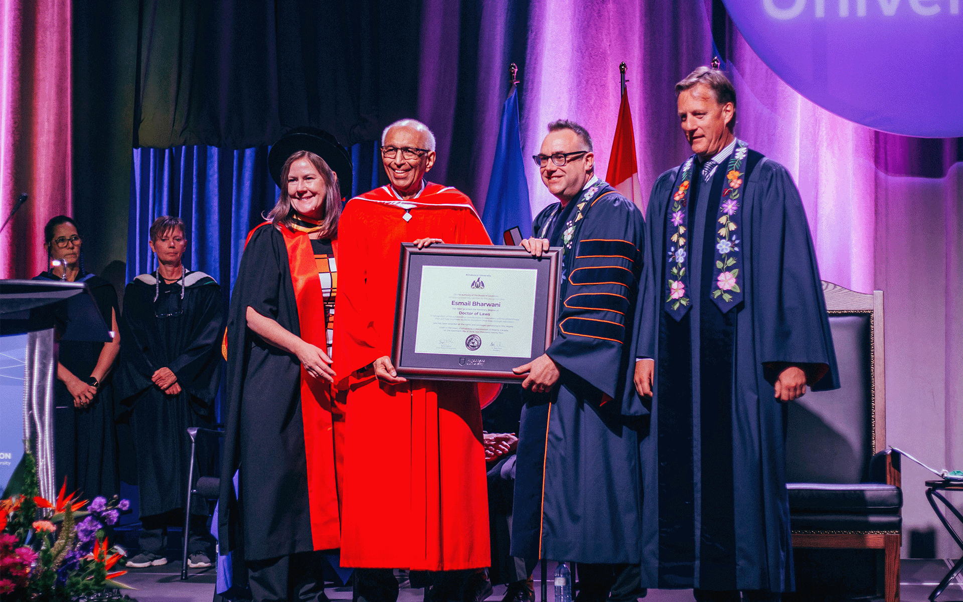 Esmail Bharwani A woman and three men standing together with one of them holding a large framed document for Esmail Bharwani's Honorary Doctor of Laws during the convocation ceremony