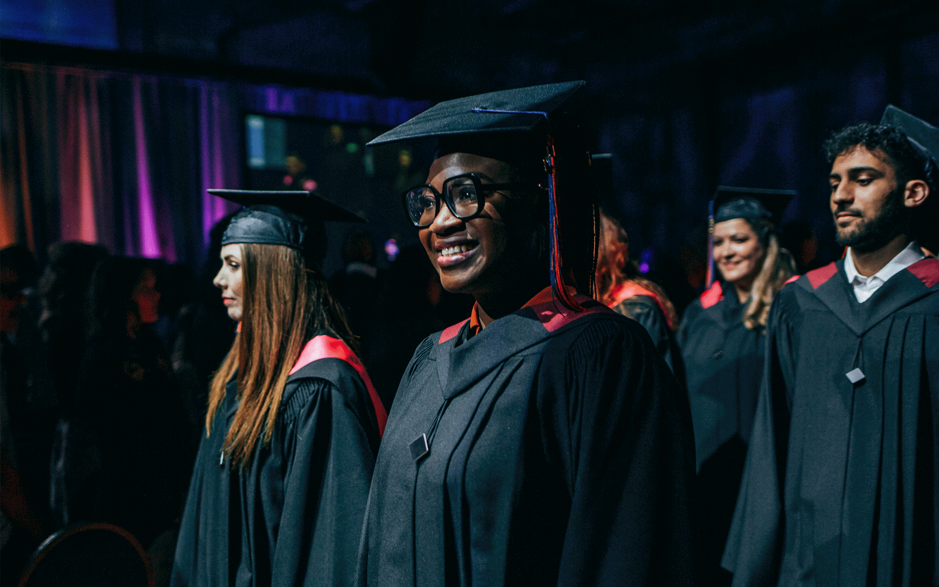 Smiling grad Graduates walking into the ceremony in a procession. Image is focused on a smiling woman