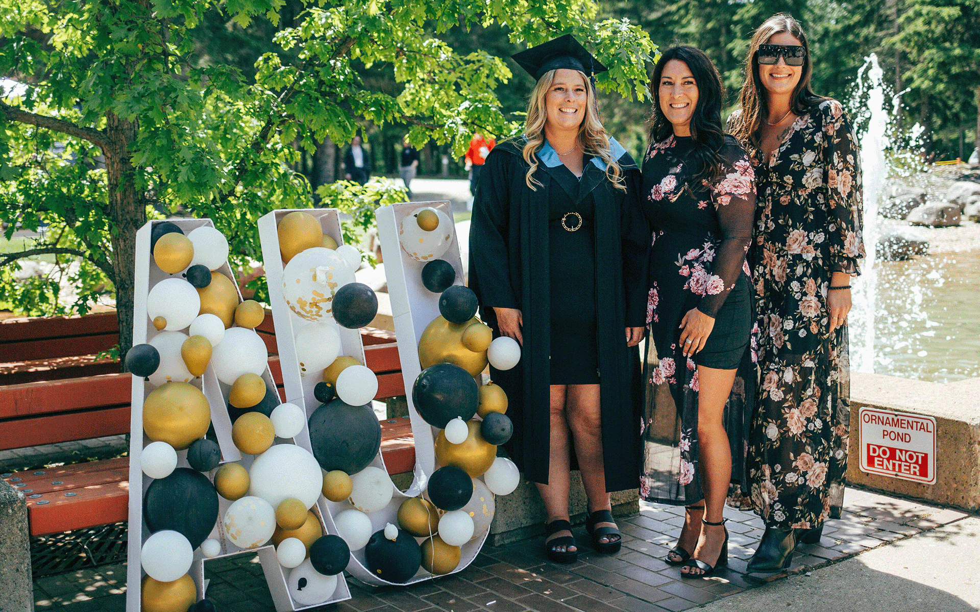 grad with family by AU sign a grad and her two family members posing for a photo next to a balloon AU sign